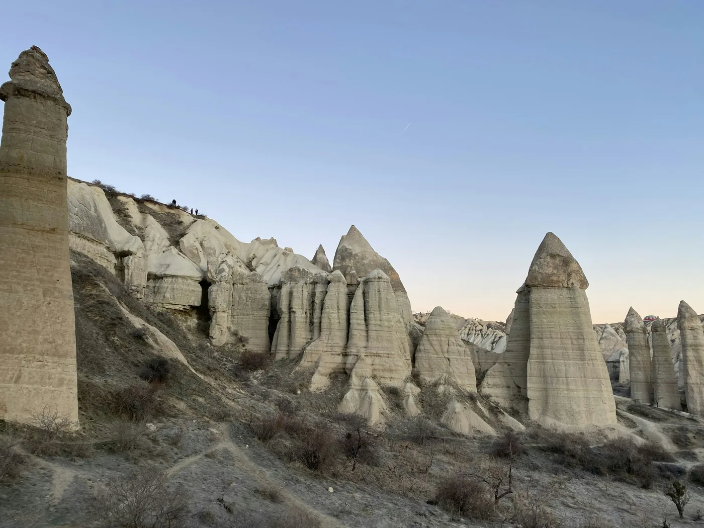 Riders crossing a dirt track between Cappadocia's carved valley walls